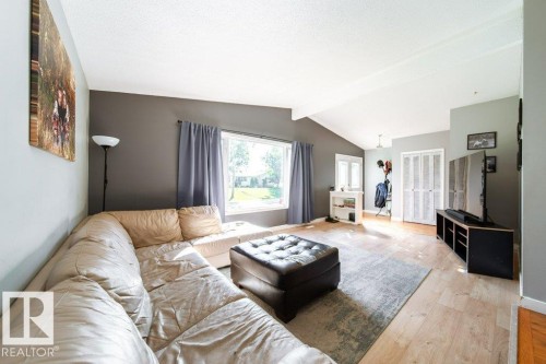 Spacious living area featuring vaulted ceilings, wood-finish flooring, and large windows with natural light - 20 Chippewa Rd, Leduc, AB 