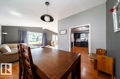 Dining area featuring wood-finish flooring and a contemporary pendant light fixture - 20 Chippewa Rd, Leduc, AB 
