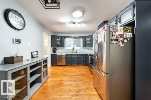 Kitchen featuring wood-finish flooring, dark cabinetry, and stainless steel appliances - 20 Chippewa Rd, Leduc, AB 
