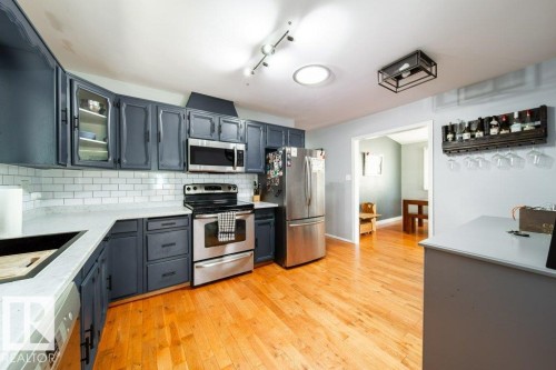 Contemporary kitchen featuring wood-finish flooring, dark cabinetry, and light countertops - 20 Chippewa Rd, Leduc, AB 