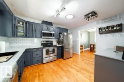 Contemporary kitchen featuring wood-finish flooring, dark cabinetry, and light countertops - 