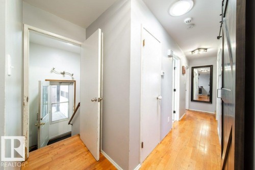 Hardwood flooring throughout a hallway featuring a circular ceiling light and a dark wood-finish barn door - 20 Chippewa Rd, Leduc, AB 