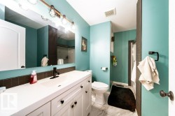 Bathroom featuring a large vanity with white cabinetry, a built-in sink, and a matte black faucet - 