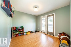 Room featuring wood-finish flooring, light green walls, a ceiling-mounted light fixture, and double glass-paned doors providing natural light - 