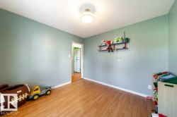 Room featuring wood-finish flooring, light blue-green wall color, and white baseboards - 
