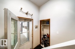 Entryway featuring a decorative glass storm door, a solid panel main door, an integrated wall light fixture, and a built-in closet with a wooden frame and shelf - 