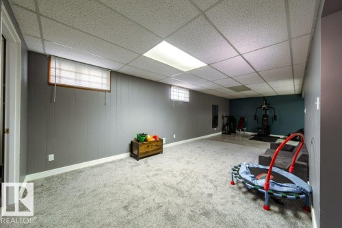 Carpeted room featuring acoustic panel ceiling, recessed lighting, and paneling on the perimeter walls - 20 Chippewa Rd, Leduc, AB 