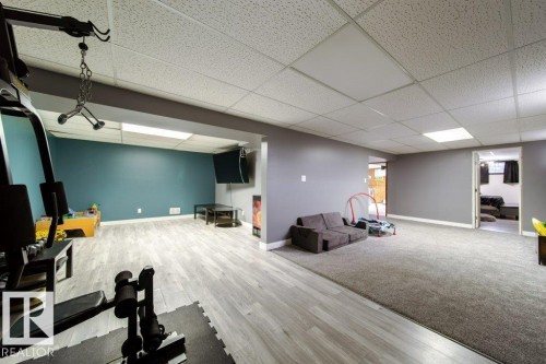 Spacious lower level featuring a combination of wood-finish flooring and carpet, drop ceiling with integrated lighting, and a neutral color palette - 20 Chippewa Rd, Leduc, AB 