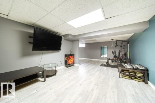 Spacious open area featuring light wood-finish flooring and a drop ceiling with recessed lighting - 20 Chippewa Rd, Leduc, AB 