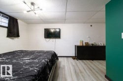 Bedroom featuring light wood-finish flooring, white walls, and a statement green accent wall - 
