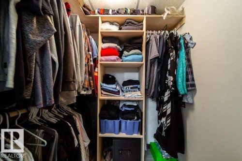 Custom closet organization system featuring wooden shelving and multiple hanging rods - 20 Chippewa Rd, Leduc, AB 