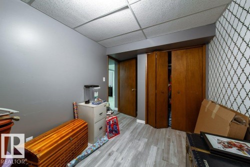 Room featuring wood-finish flooring, drop ceiling, and bi-fold closet doors - 20 Chippewa Rd, Leduc, AB 