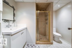 Bathroom featuring a glass-enclosed shower with tiled walls, a white vanity with an integrated sink, and a drop ceiling with recessed lighting - 