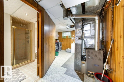 Utility space featuring a furnace, exposed ductwork, and wood-paneled walls - 20 Chippewa Rd, Leduc, AB 