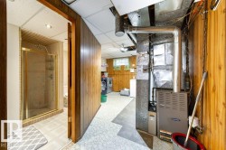 Utility space featuring a furnace, exposed ductwork, and wood-paneled walls - 