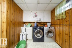Dedicated laundry area featuring wood-panel walls, a drop ceiling, and a high window - 