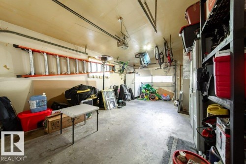 Spacious garage featuring concrete flooring and exposed ceiling beams - 20 Chippewa Rd, Leduc, AB 
