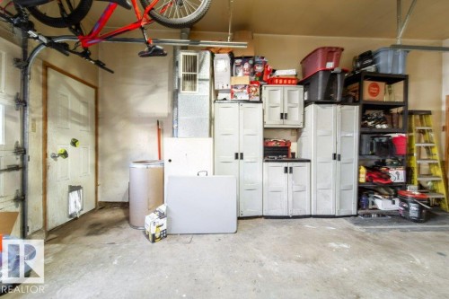 Concrete flooring garage with an overhead storage rack, interior door, and built-in storage cabinets - 20 Chippewa Rd, Leduc, AB 