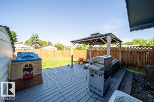 Expansive backyard featuring a wood-finish deck, a built-in gazebo structure, and a perimeter wood fence - 20 Chippewa Rd, Leduc, AB 