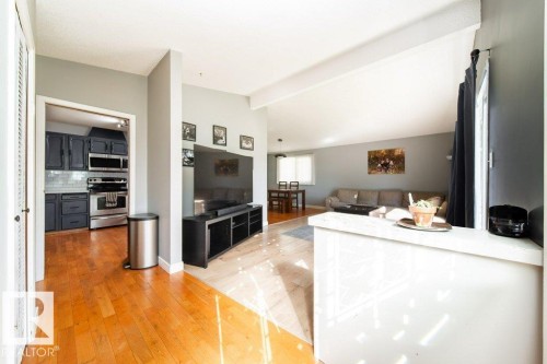 Open-concept living area with wood-finish flooring extending into the kitchen - 20 Chippewa Rd, Leduc, AB 