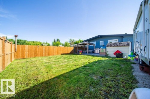 Expansive backyard featuring a privacy fence, a dedicated patio area with a gazebo, and a detached storage shed - 20 Chippewa Rd, Leduc, AB 