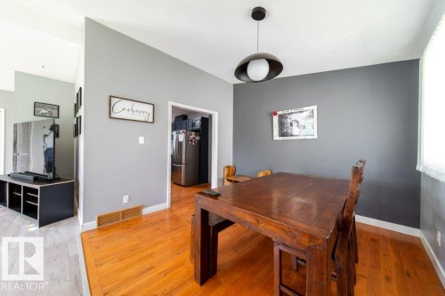 Dining area featuring wood-finish flooring and a contemporary pendant light fixture - 20 Chippewa Rd, Leduc, AB 