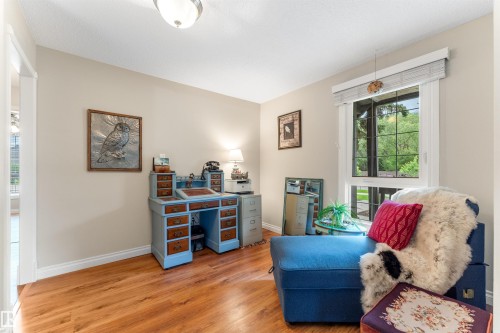 Room featuring wood-finish flooring, neutral wall paint, and a large window with white trim and blinds - 5802 172 Street, Edmonton, AB 
