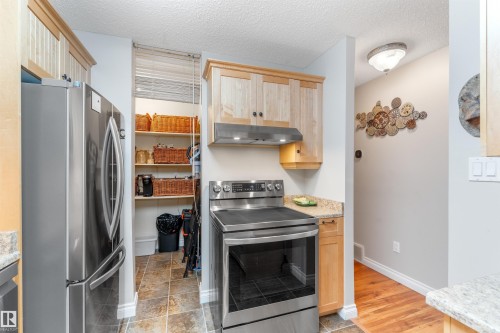 Kitchen area featuring stainless steel appliances including a refrigerator and range with an overhead microwave/ventilation unit - 5802 172 Street, Edmonton, AB 