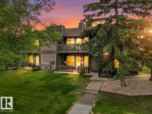 Multi-story residence featuring a dark gray facade, two private balconies with wooden railings, and multiple windows - 5802 172 Street, Edmonton, AB 