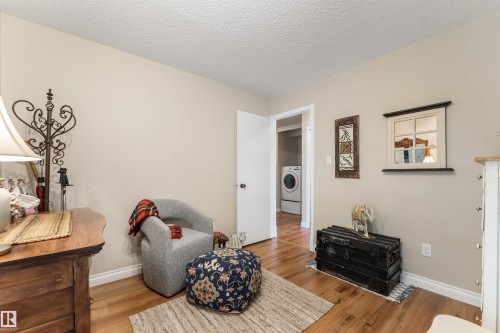 Wood-finish flooring extends throughout this interior space, featuring light-toned walls and crisp white trim - 5802 172 Street, Edmonton, AB 
