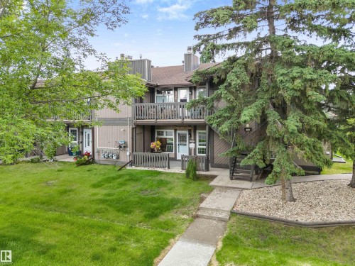 Multi-level residence featuring a brown siding exterior, individual balconies with wooden railings, and a concrete pathway - 5802 172 Street, Edmonton, AB 