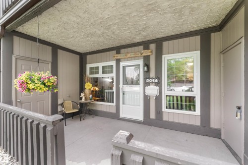 Covered porch featuring painted wood siding, a recessed entry, and a white storm door - 5802 172 Street, Edmonton, AB 