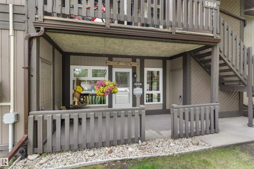 Ground-level entry featuring a covered patio, white-framed windows, and an exterior staircase - 5802 172 Street, Edmonton, AB 