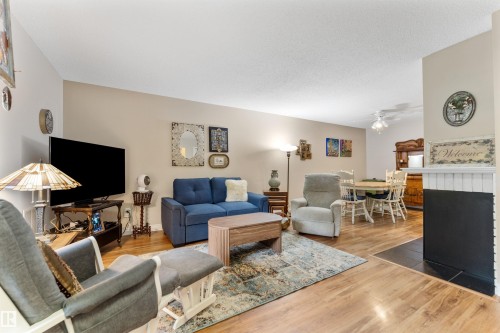 Spacious living area featuring wood-finish flooring, a neutral wall palette, and a built-in fireplace with a hearth - 5802 172 Street, Edmonton, AB 