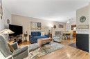 Spacious living area featuring wood-finish flooring, a neutral wall palette, and a built-in fireplace with a hearth - 5802 172 Street, Edmonton, AB 