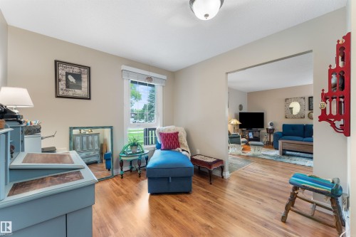Bright interior space featuring wood-finish flooring, a window with horizontal blinds, and a neutral wall color - 5802 172 Street, Edmonton, AB 