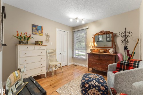 Neutral-toned room featuring a window with blinds, wood-finish flooring, and a white bi-fold door - 5802 172 Street, Edmonton, AB 