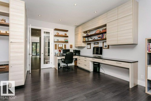 Dedicated workspace featuring extensive built-in cabinetry, dark wood-finish flooring, recessed lighting, and french doors - 9035 Saskatchewan Drive, Edmonton, AB 