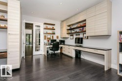 Dedicated workspace featuring extensive built-in cabinetry, dark wood-finish flooring, recessed lighting, and french doors - 