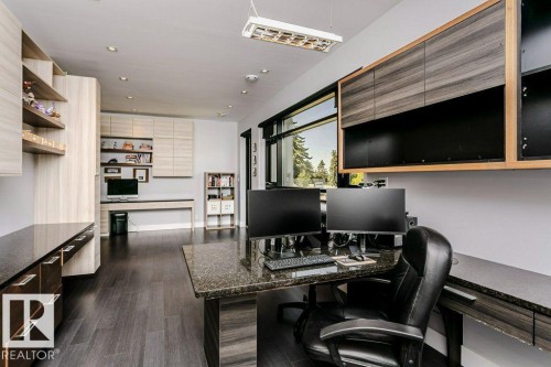 Dedicated workspace featuring dark wood-finish flooring, extensive built-in cabinetry, granite-finish countertops, recessed lighting, and large picture windows - 9035 Saskatchewan Drive, Edmonton, AB 