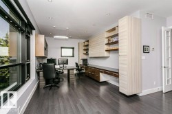 Hardwood flooring with a gray finish, custom built-in cabinetry, modern lighting, recessed ceiling lights, and multiple windows - 