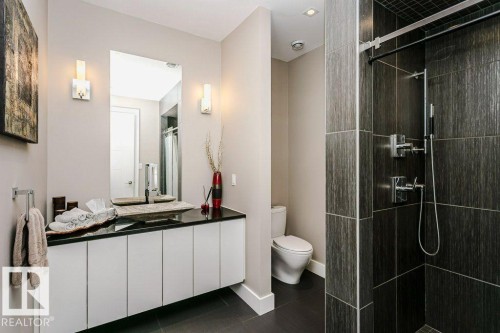 Bathroom featuring a floating vanity with a dark countertop and vessel sink, illuminated by twin sconces - 9035 Saskatchewan Drive, Edmonton, AB 