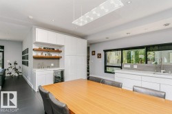 Contemporary kitchen featuring a full-height pantry, integrated wet bar with beverage cooler, under-cabinet lighting, and a large window above the sink - 