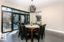 Dining area featuring dark wood-finish flooring, recessed lighting, and a contemporary chandelier - 