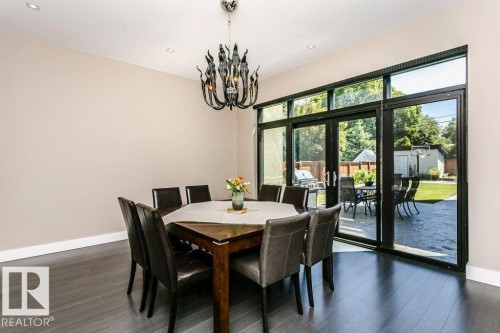 Spacious room featuring dark wood-finish flooring and a contemporary chandelier - 9035 Saskatchewan Drive, Edmonton, AB 