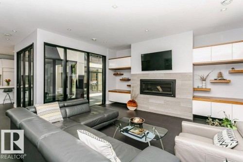 Open-concept living space featuring a modern fireplace with a tiled surround, recessed lighting, and dark tile flooring - 9035 Saskatchewan Drive, Edmonton, AB 