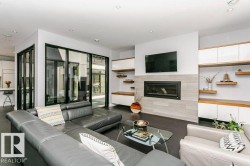 Open-concept living space featuring a modern fireplace with a tiled surround, recessed lighting, and dark tile flooring - 