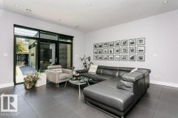 Spacious living area featuring large format tile flooring, recessed lighting, expansive glass sliding doors, and a high ceiling - 