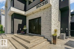 Modern exterior featuring multi-level concrete steps, black double entry doors with decorative inserts, stacked stone accent wall, and dark stucco siding - 