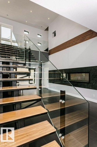 Modern floating staircase featuring wood-finish treads and clear glass railings - 9035 Saskatchewan Drive, Edmonton, AB 